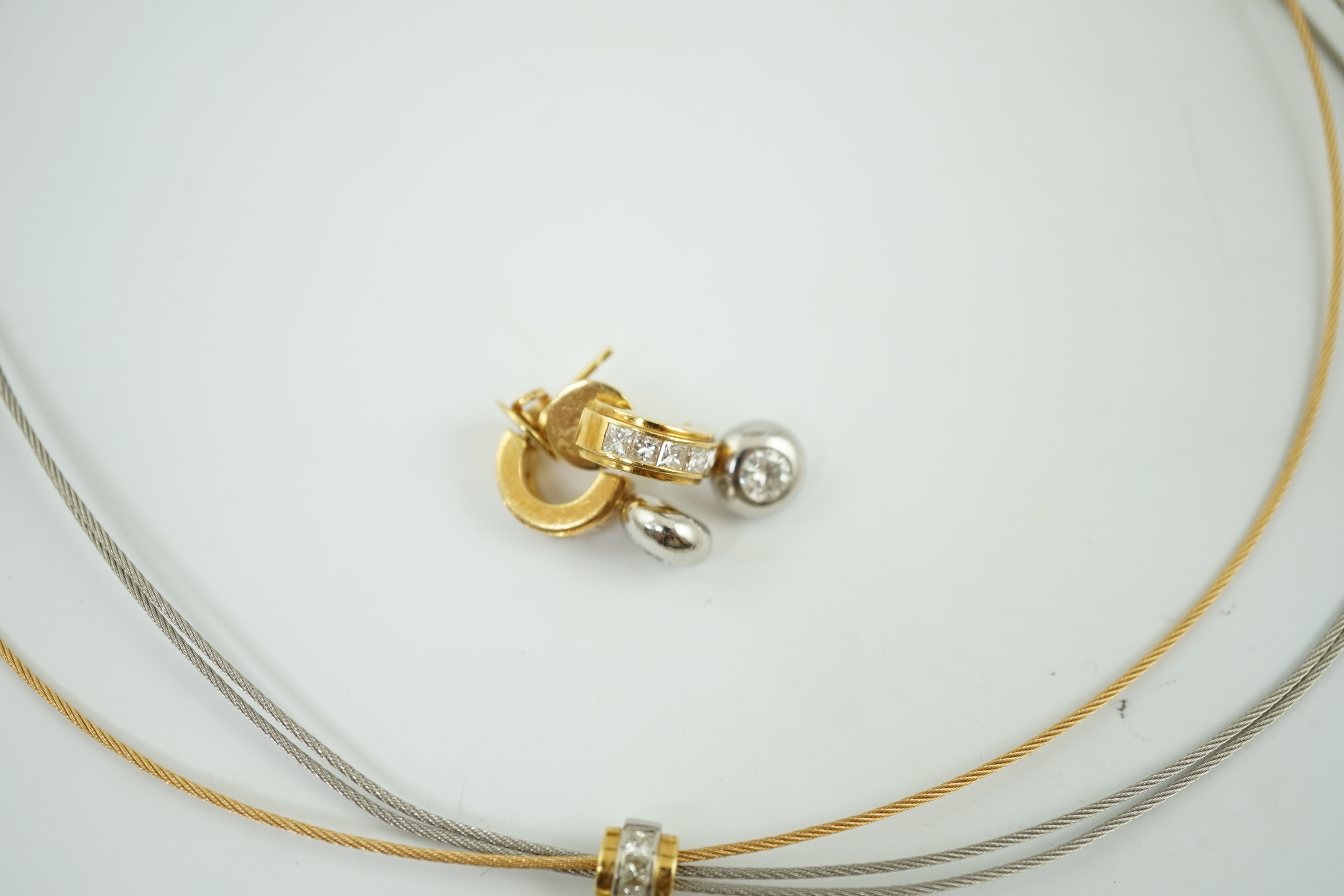 A modern platinum and 18k gold triple strand necklet, with round and princess cut diamond set pendant and a pair of matching earrings